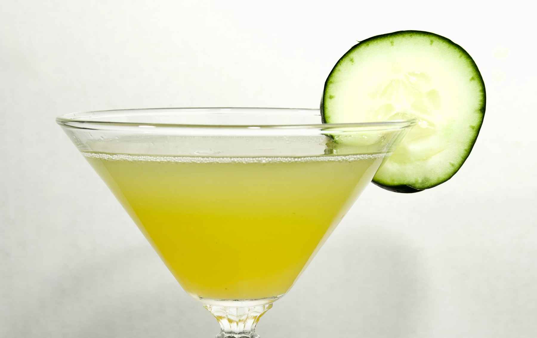 Cocktail in a martini dress garnished with a cucumber slice.