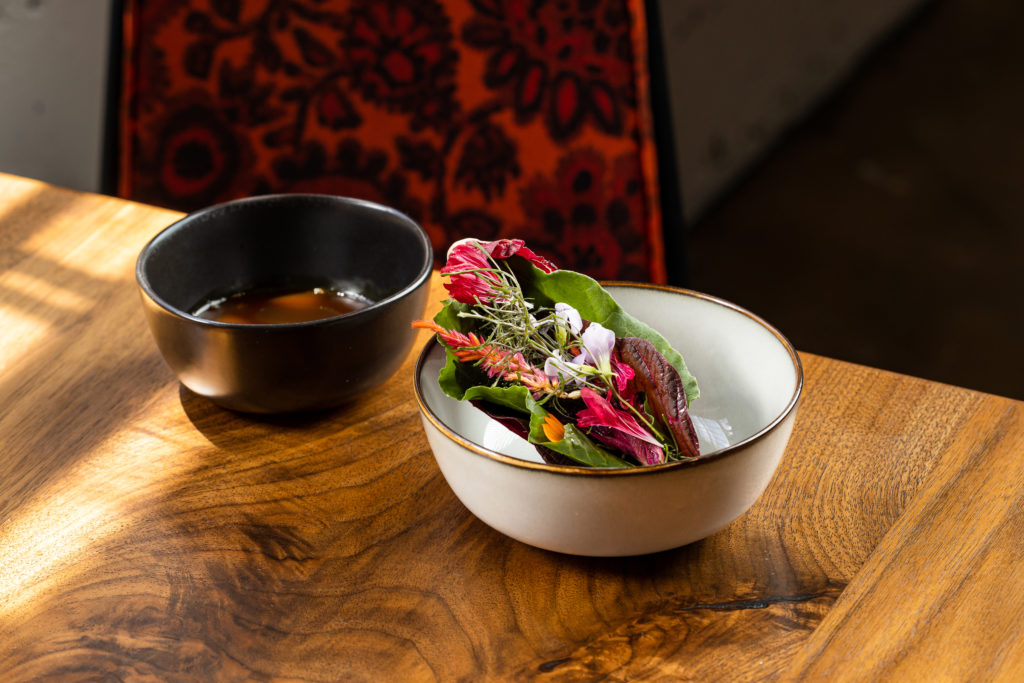 A dish of fresh farm-to-table cuisine and mixed greens from Koko Ni restaurant in Denver, Colorado