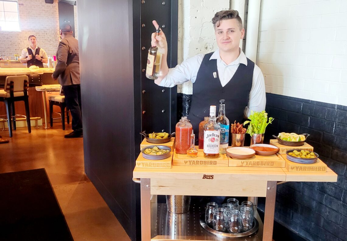 man with liquor bottle in front of bloody mary cart