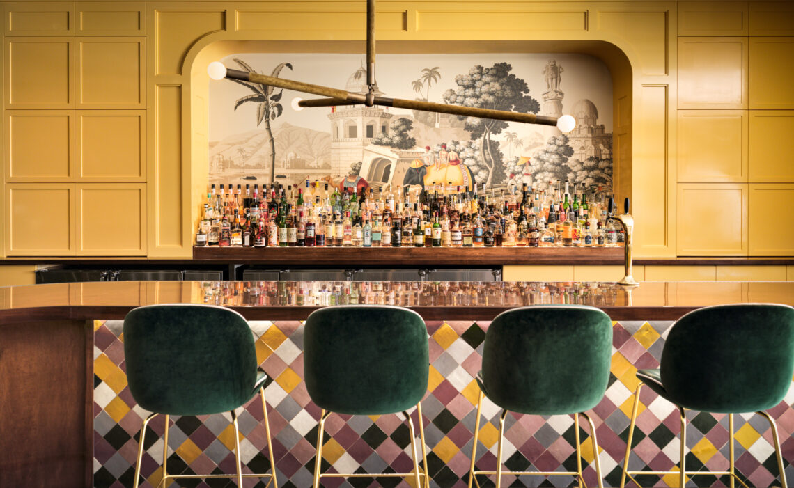four green chairs in front of bar with mural