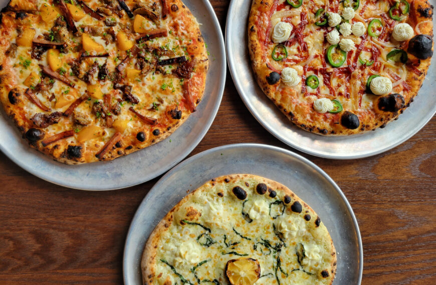 three pizzas on a wood table