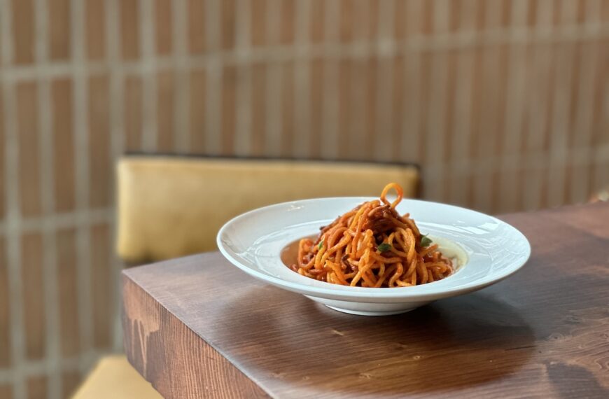 brown table with white bowl filled with red pasta
