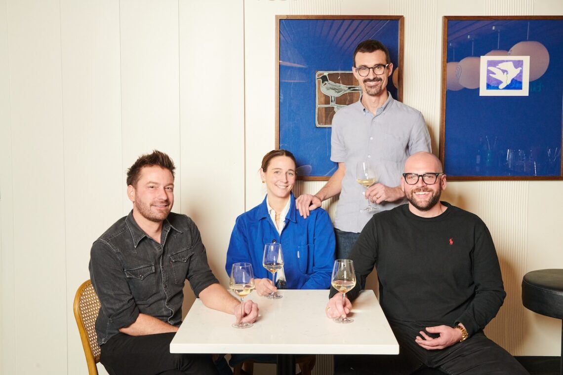 four people sitting at table with wine glasses