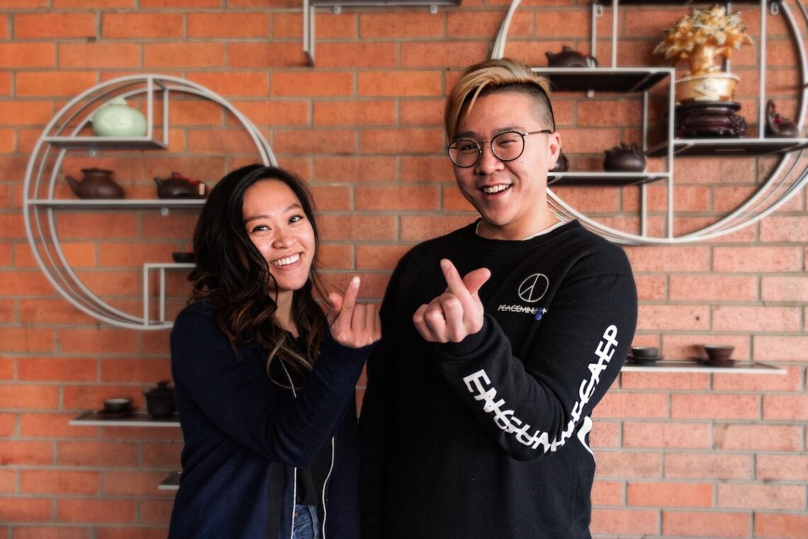 brick wall with two asian people standing in front