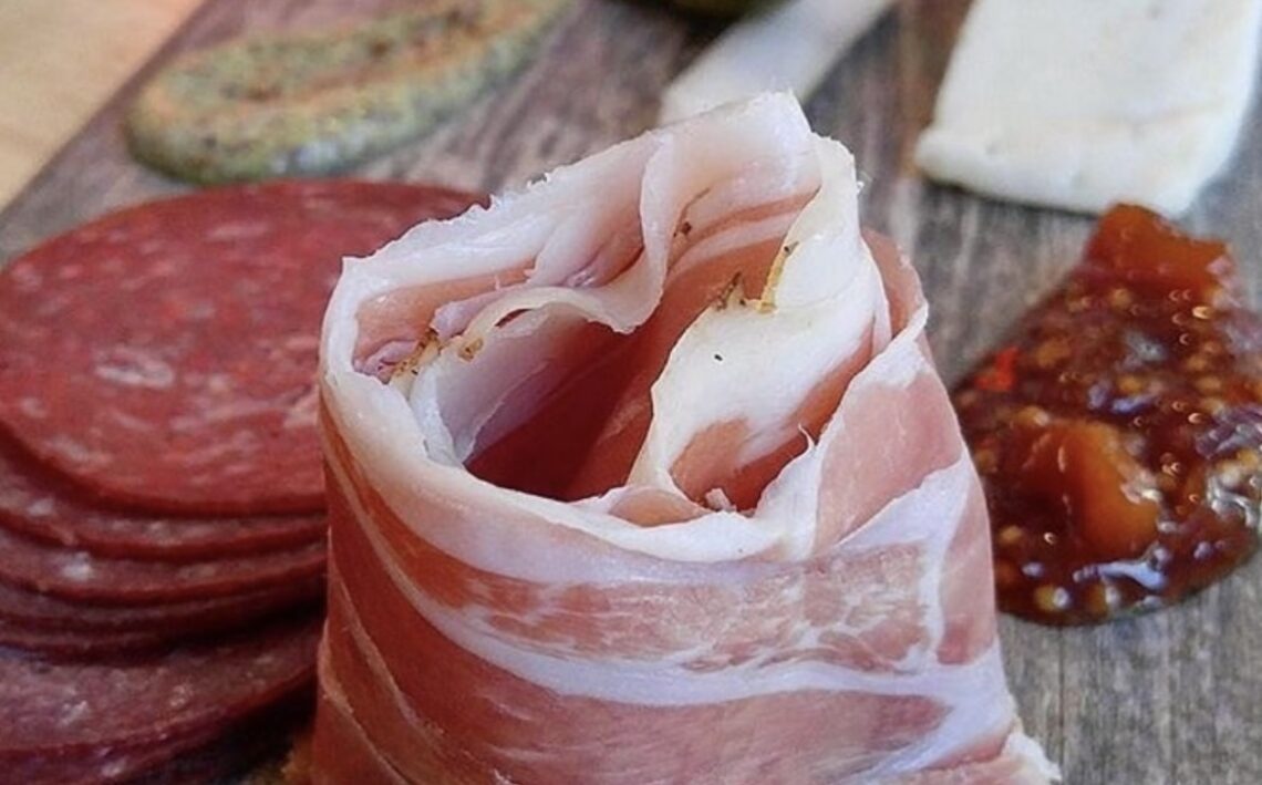 curl of meat with salumi behind and jam