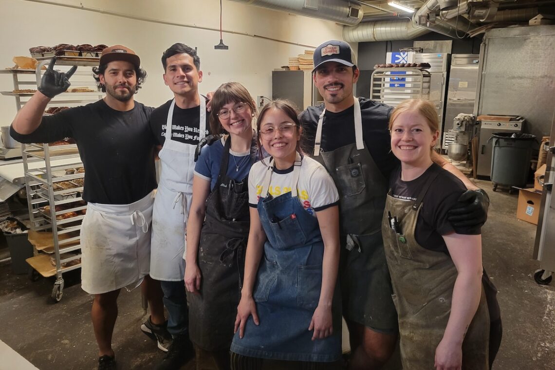 group of people wearing aprons in a bakery