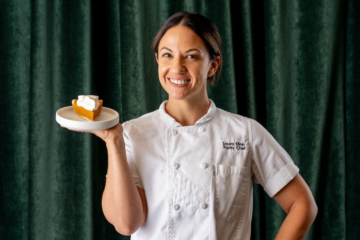 white woman in chef coat holding pie