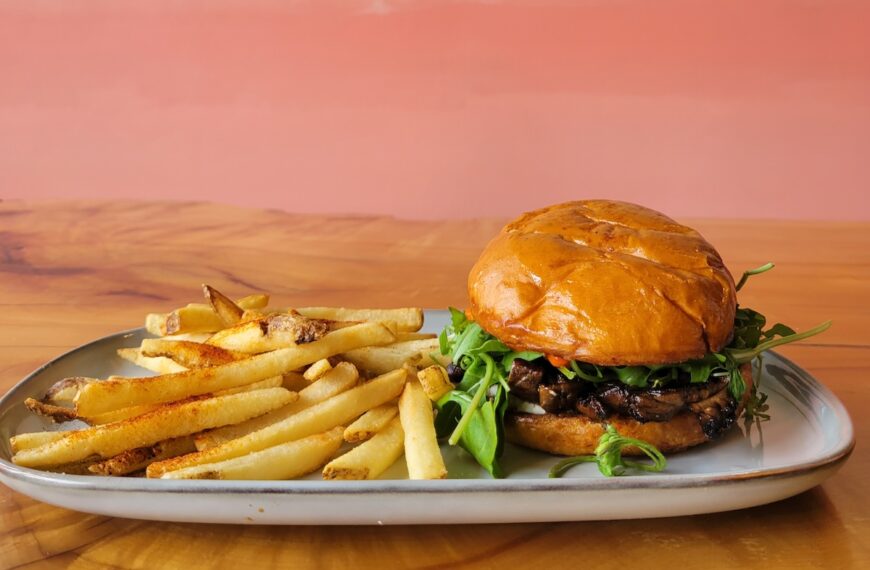 pink wall with burger and fries on a plate