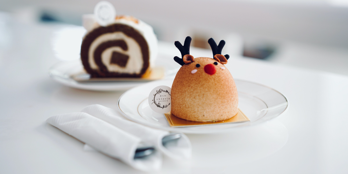 A pastry shaped like a holiday reindeer on a white plate on a white tablecloth