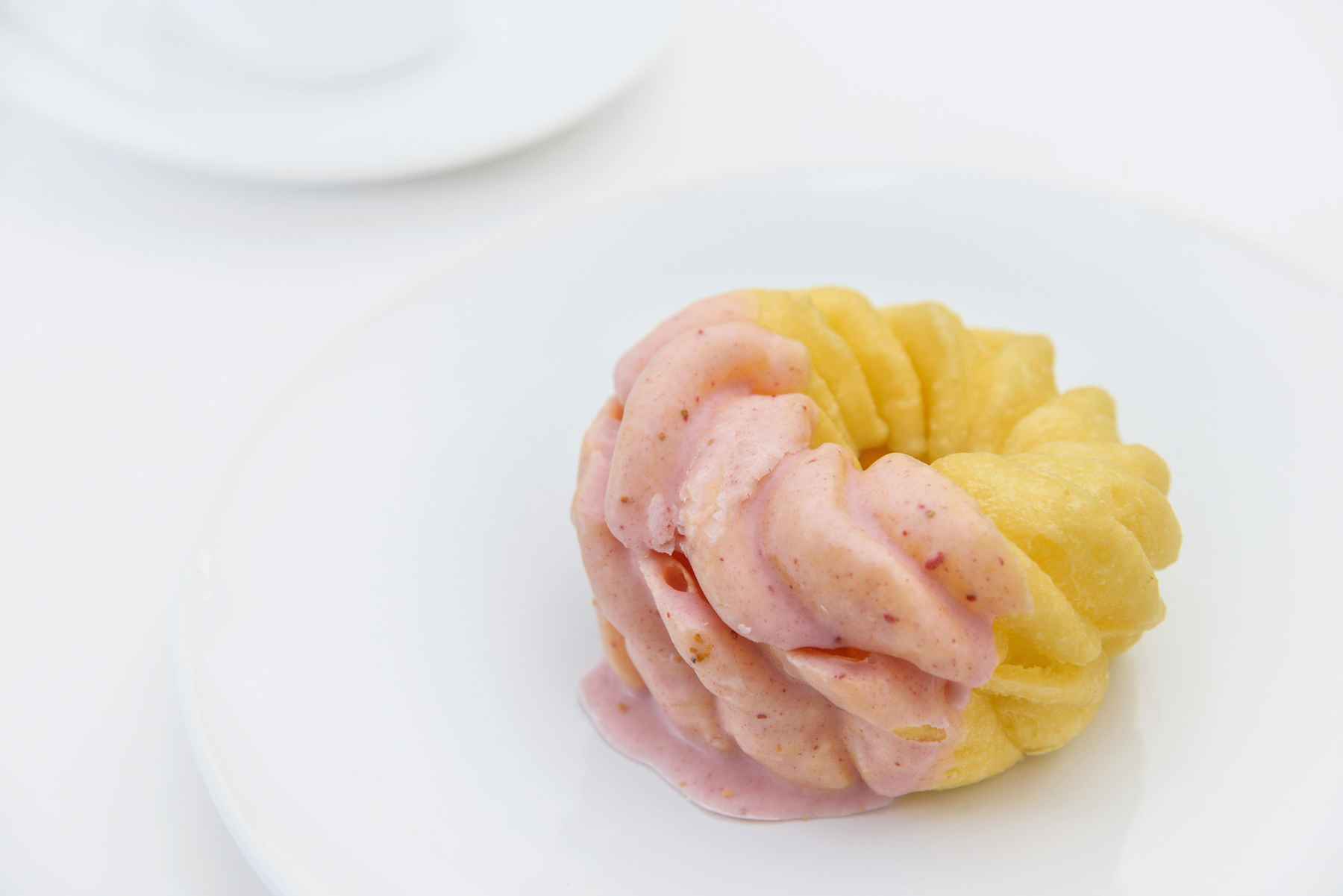 French cruller doughnut with strawberry glaze on a plate.