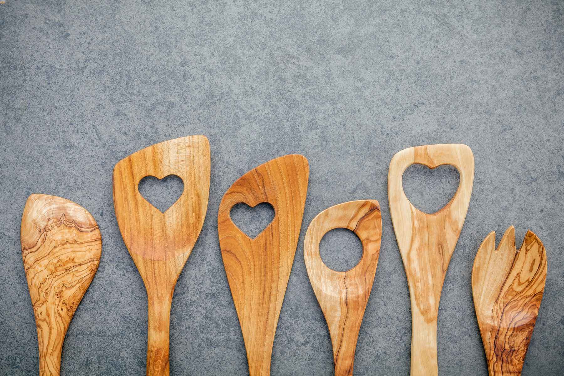Selection of wooden kitchen spoons with heart cutouts. Favorite kitchen tools.