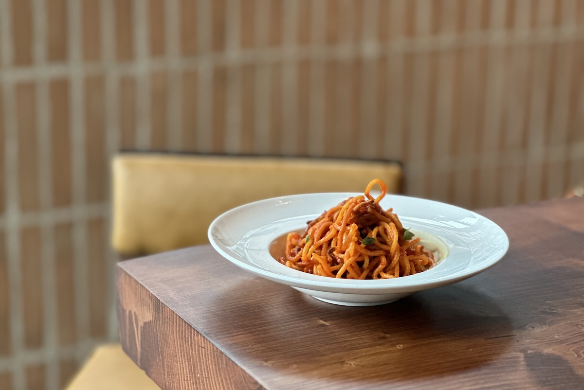 brown table with white bowl filled with red pasta