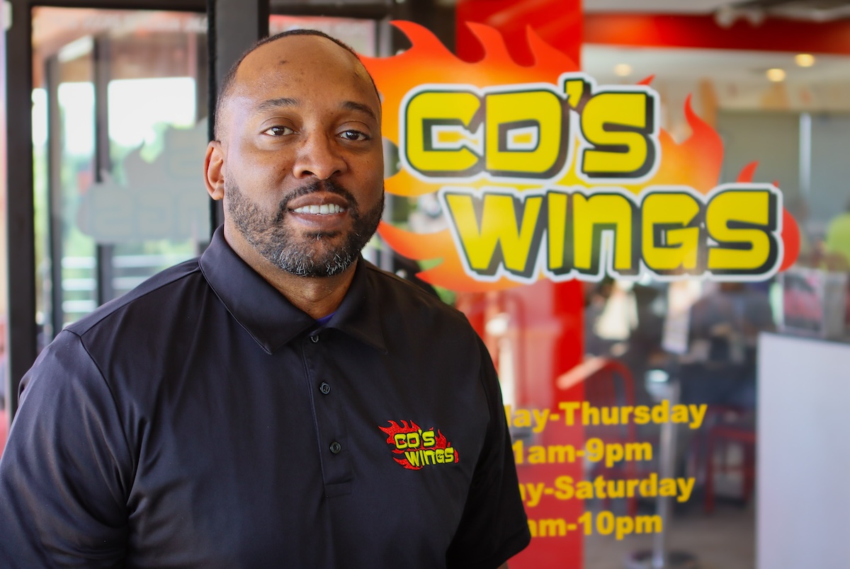 black man in front of colorful sign