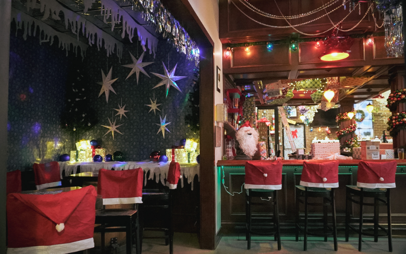A Christmas-themed bar with Santa hat decorations on the barstools and chairs at Call to Arms Brewing in Denver, Colorado