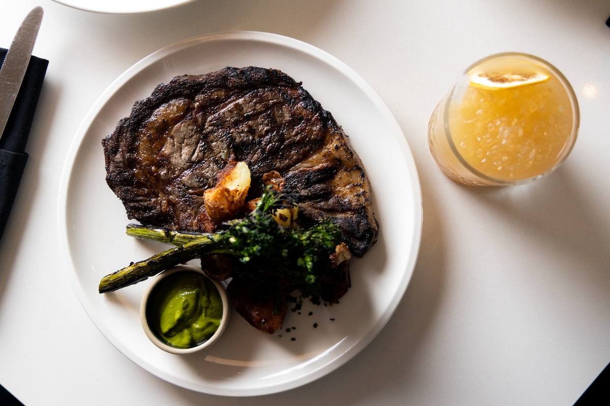 white table with steak on it and yellow drink