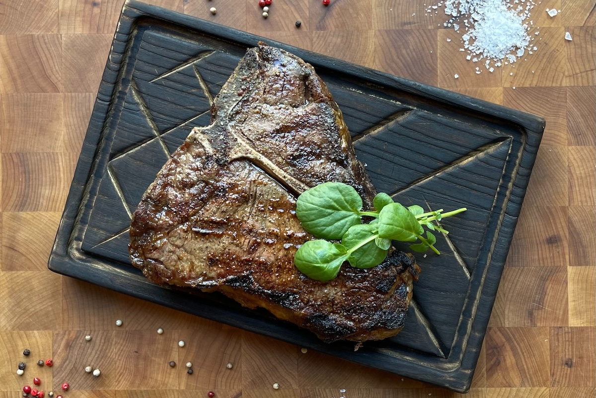 t-bone steak on black plate with basil on top