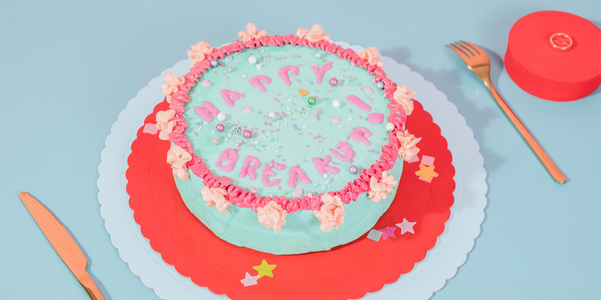 A light blue cakle with pink frosting that reads: “Happy Breakup!”