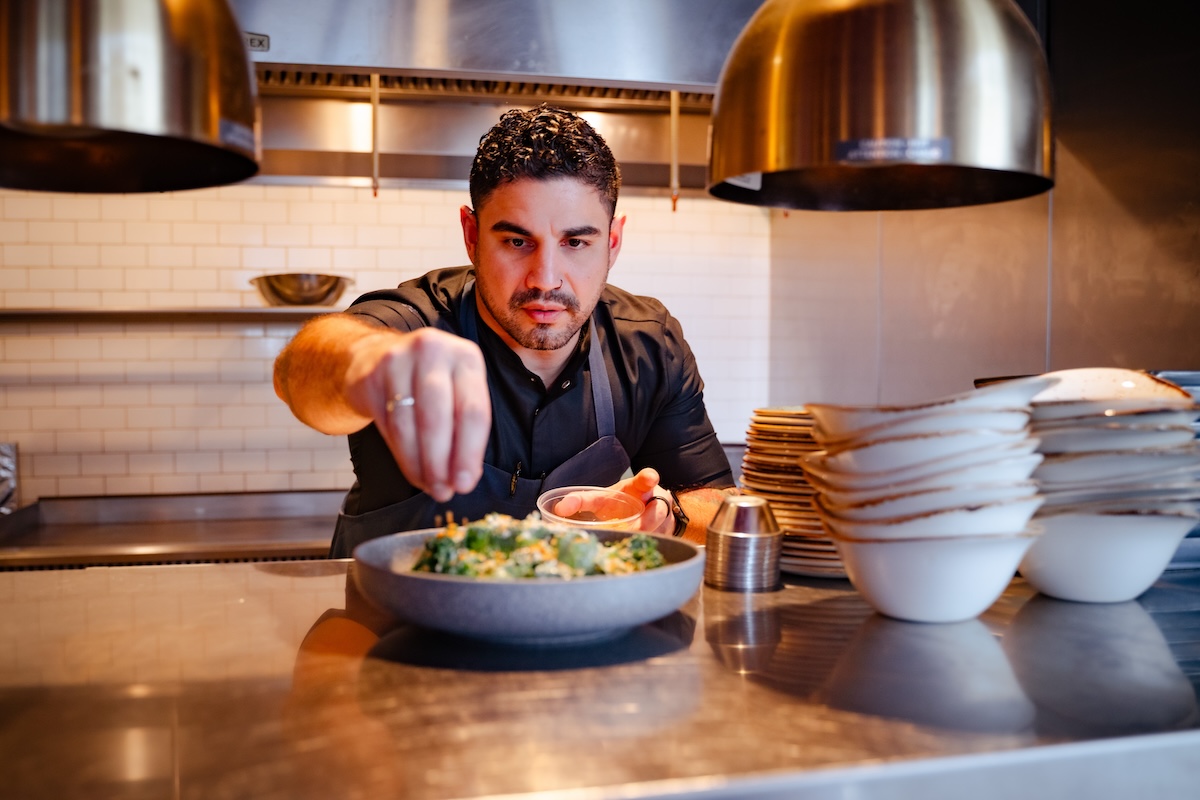 chef manny barella sprinkles salt on food in kitchen