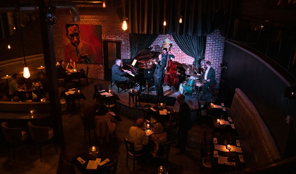 dark room with lit stage and musicians playing jazz in denver