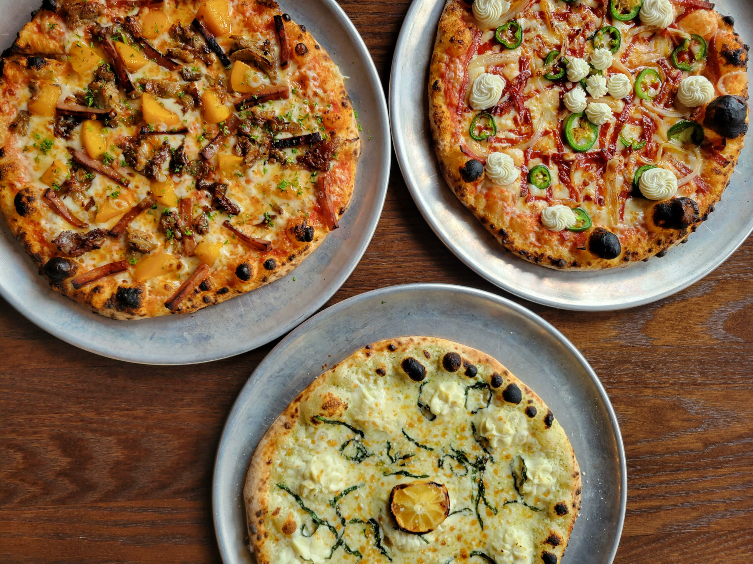 three pizzas on a wood table