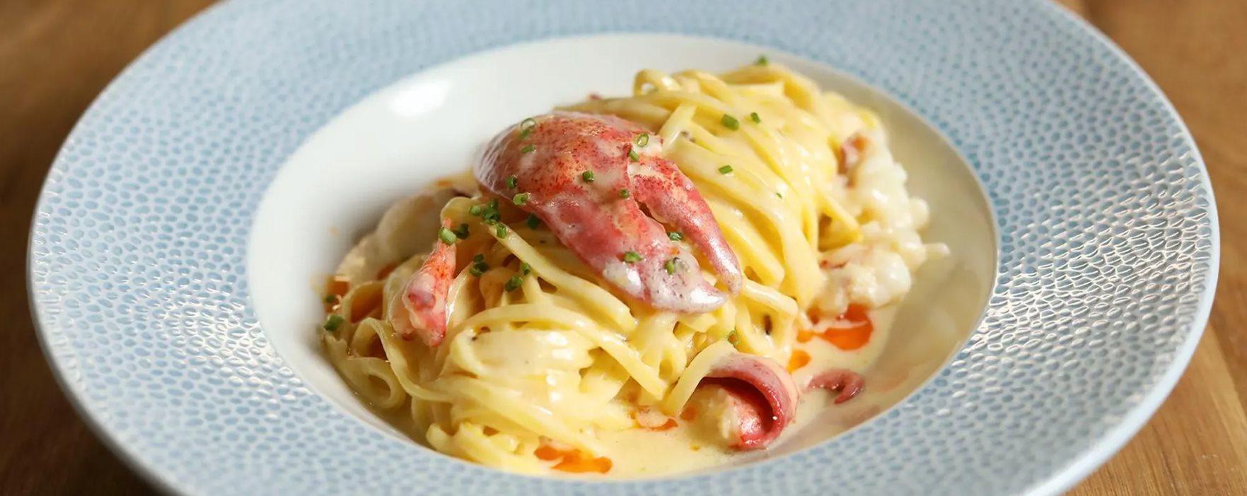 A blue and white dish filled with lobster pasta from Denver's Restaurant Olivia