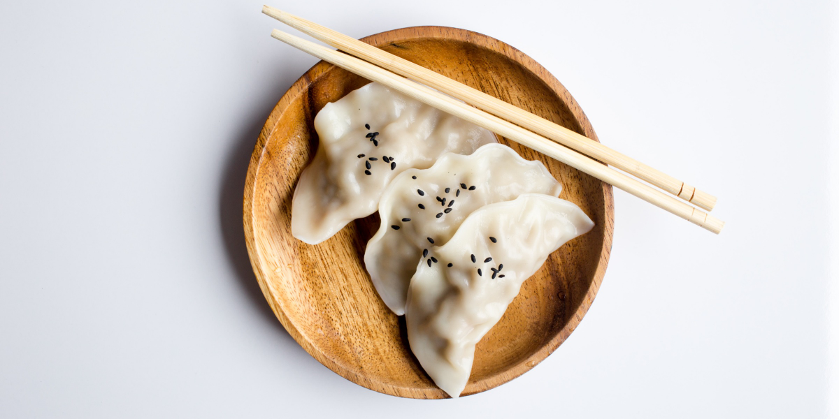 A close-up image of steaming hot dumplings on a white background, ready to be devoured.