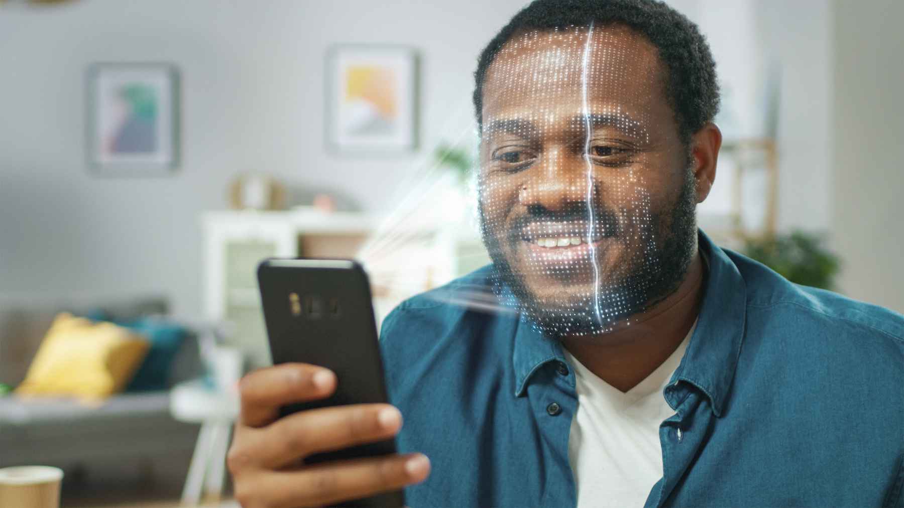Smiling Black man holding smartphone while his face is scanned for digital ID.