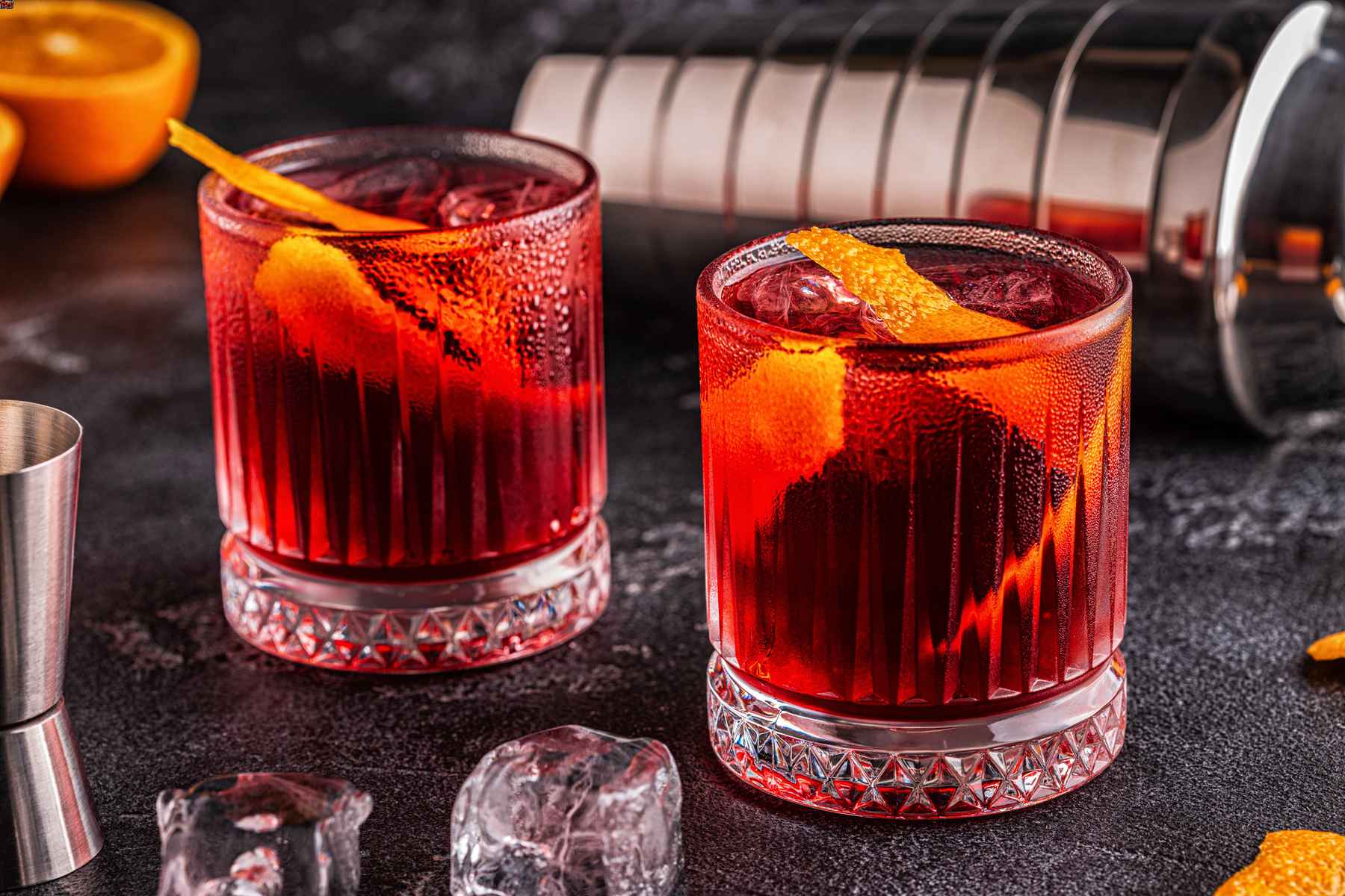 Two glasses filled with Negroni cocktails and garnished with orange peel.