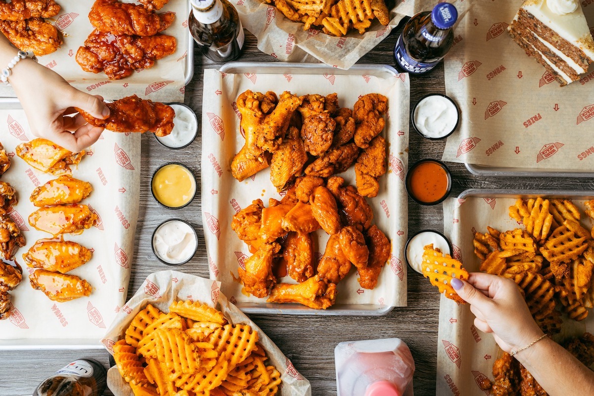 A spread of various chicken wings, waffle fries, and dipping sauces at Wang Shack. | Photo by Wang Shack