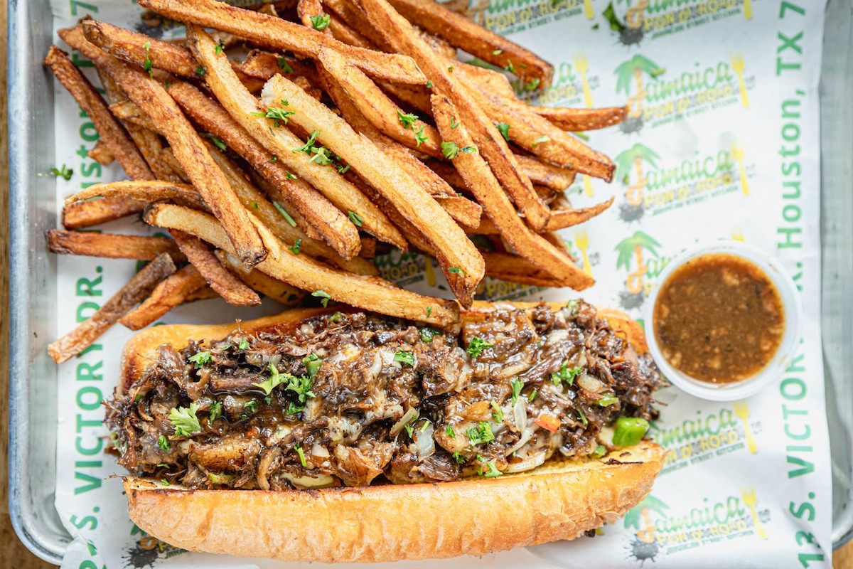 Jamaica Pon Di Road’s indulgent oxtail cheesesteak piles tender, gravy-soaked oxtail, melted provolone, and sweet peppers onto a toasted roll. | Photo by Jamaica Pon di Road