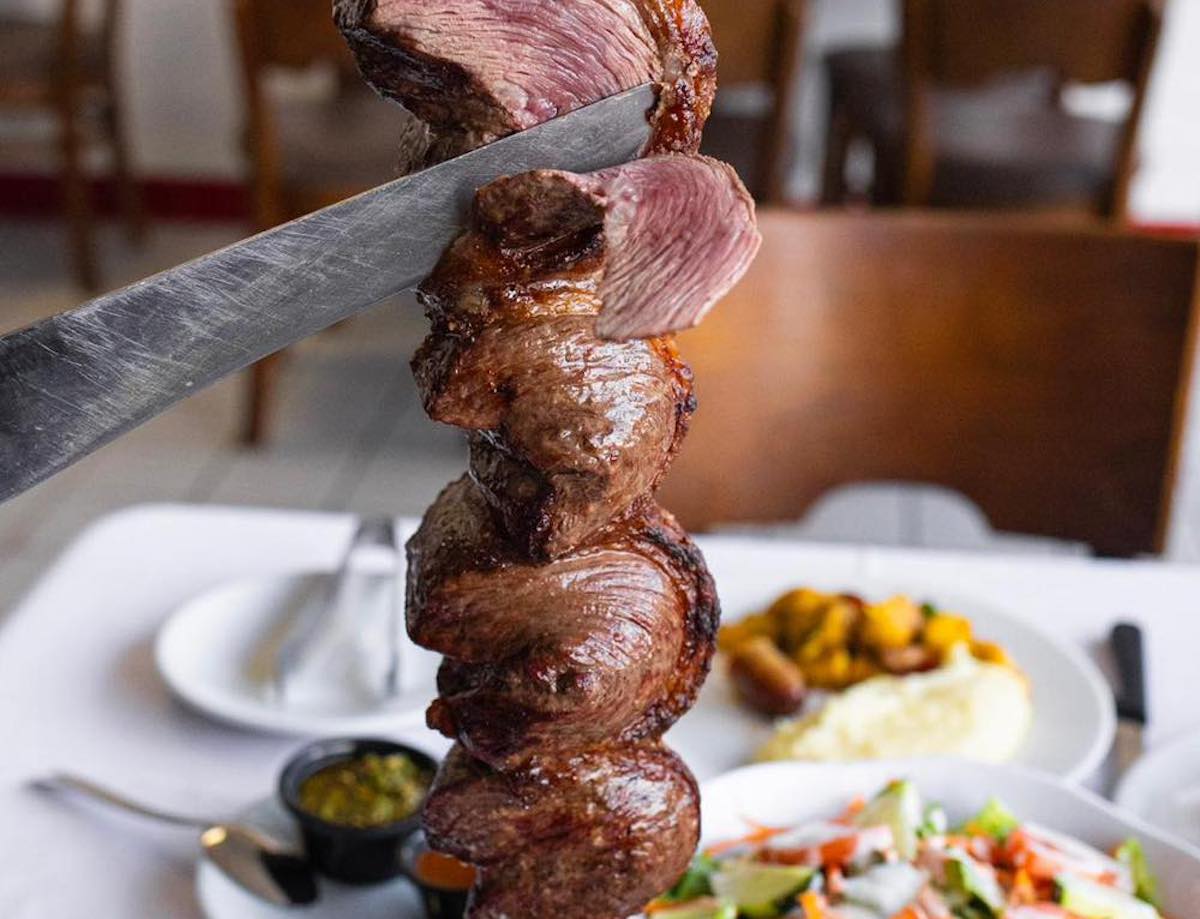 Espadas - DiningOut A signature skewer of churrasco-roasted beef is carved tableside at Espadas Brazilian Steakhouse & Catering. | Photo by Espadas Brazilian Steakhouse & Catering