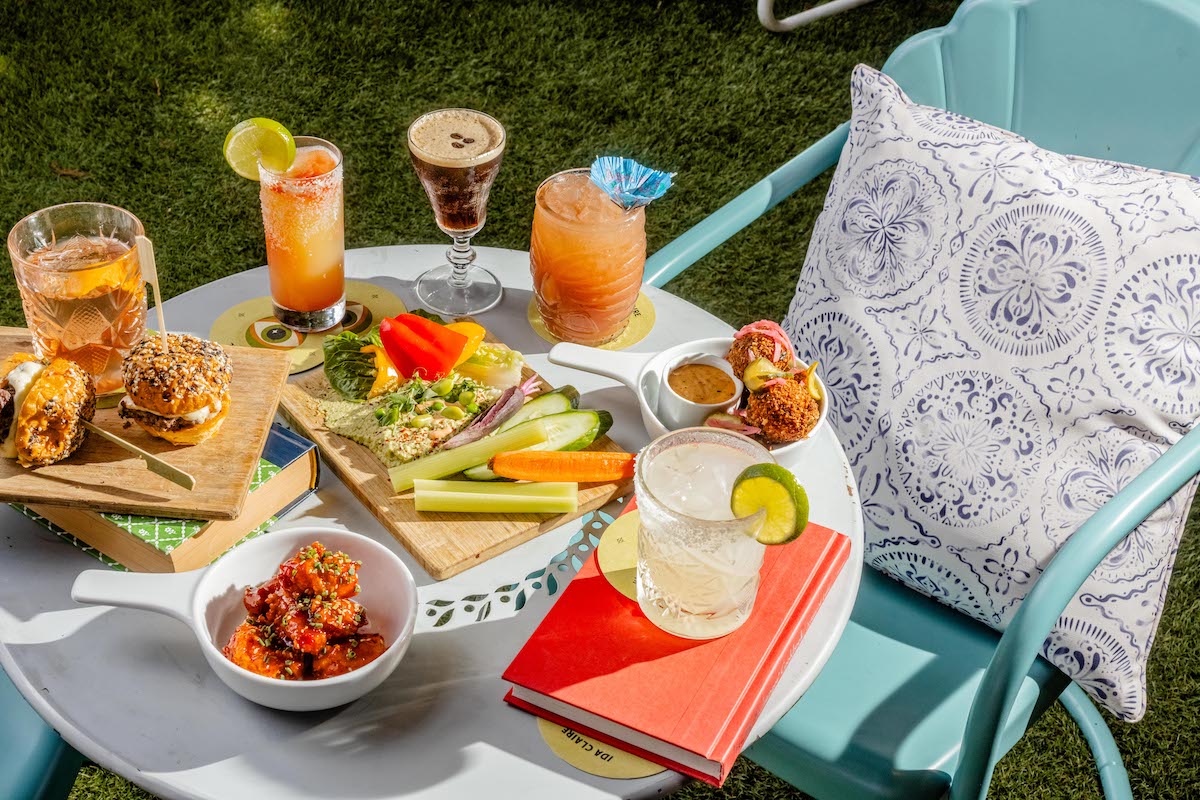 A vibrant happy hour food and cocktails spread on the patio at Ida Claire. | Photo by Ida Claire