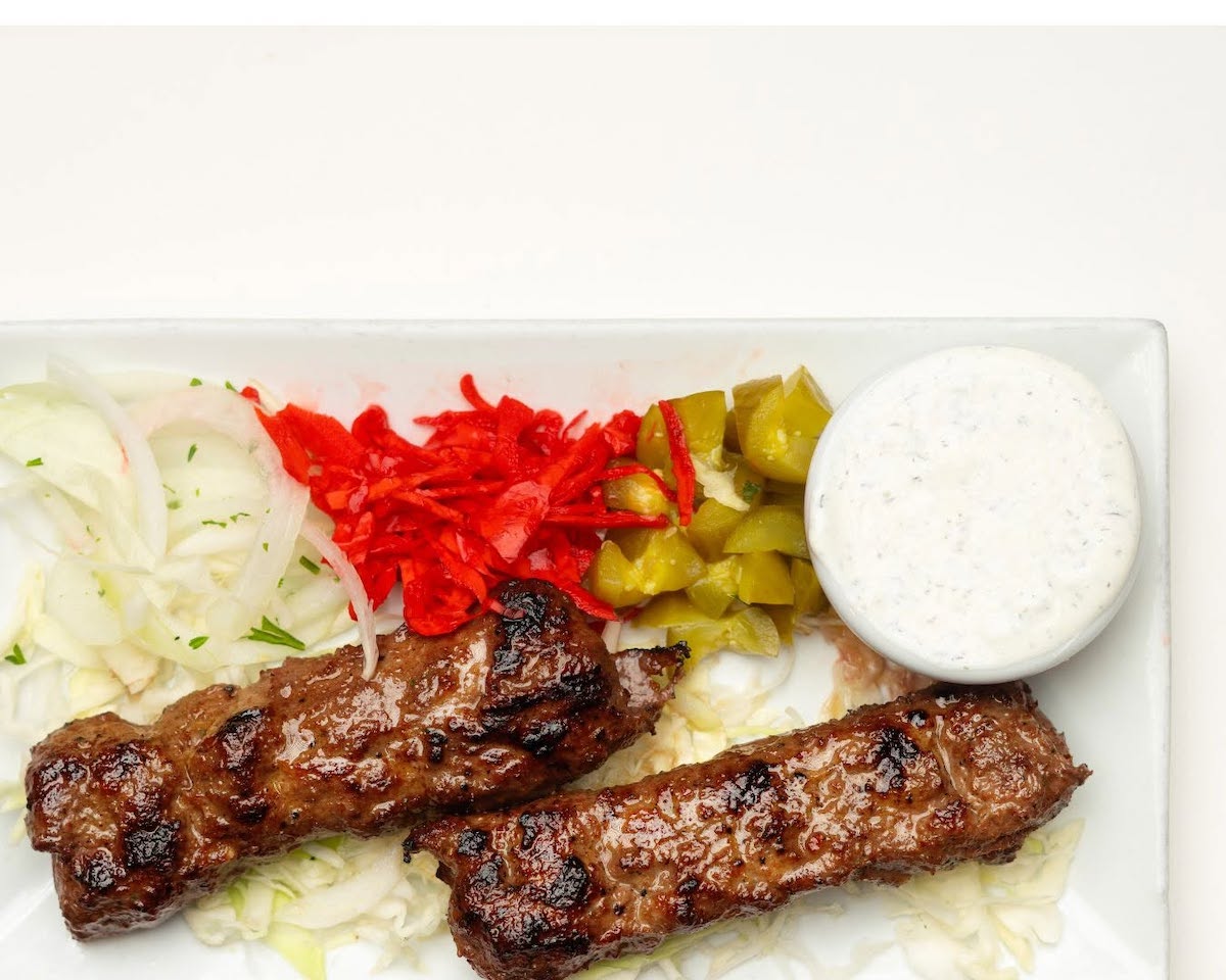 Grilled kafta kabobs served with fresh vegetables, pickled peppers, and a creamy dipping sauce at Aladdin Mediterranean Cuisine in Houston. | Photo by Aladdin Mediterranean Cuisine