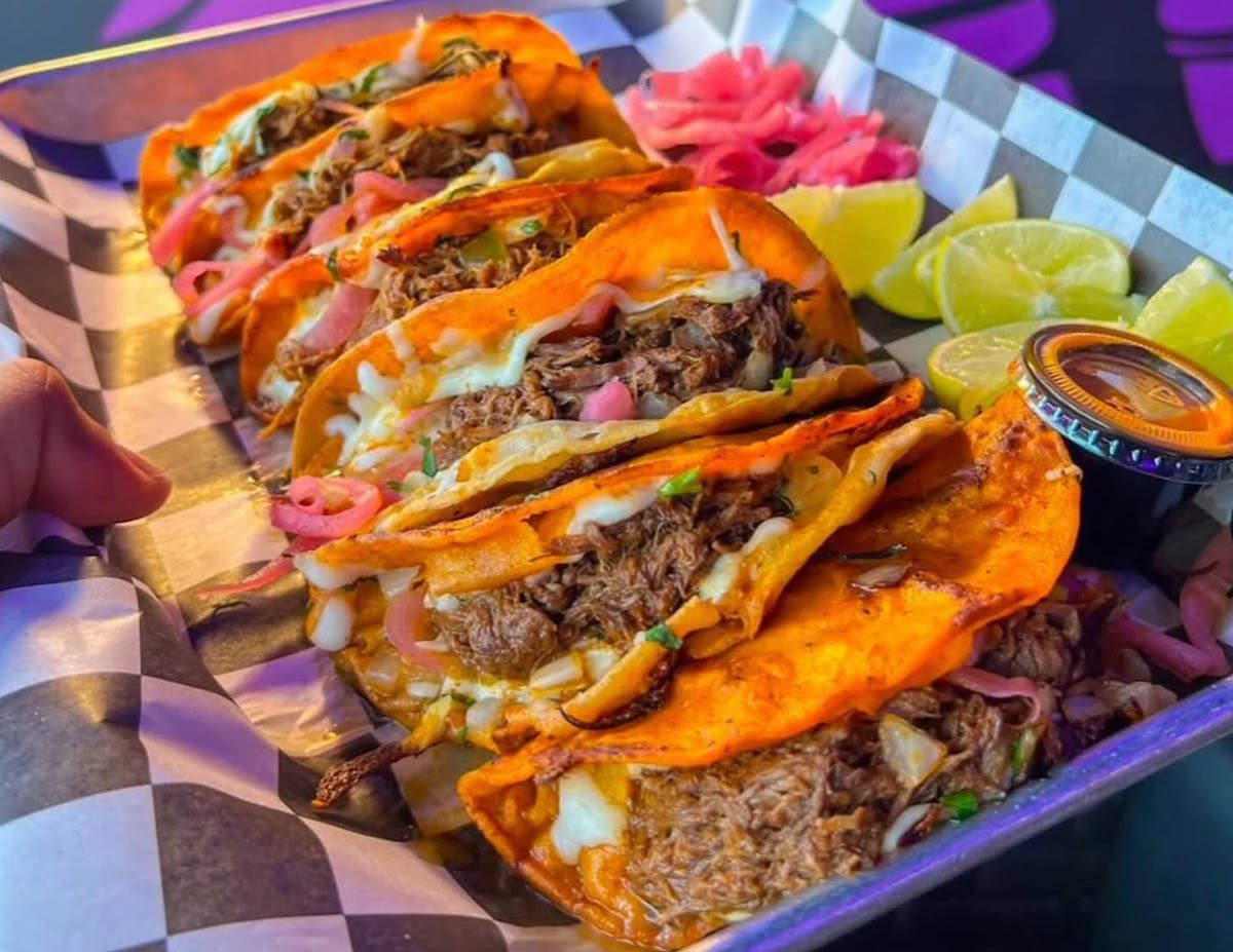 Cheesy birria tacos loaded with tender, shredded meat and served with pickled onions, fresh lime, and dipping consommé at Dripped Birria. | Photo by Dripped Birria
