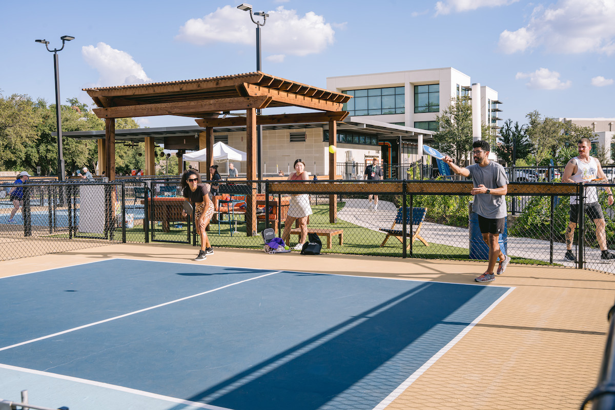 Pickleball players hit the courts at The Sandy Pickle, which also offers sand volleyball and a golf simulator alongside food and drinks. | Photo by The Sandle Pickle