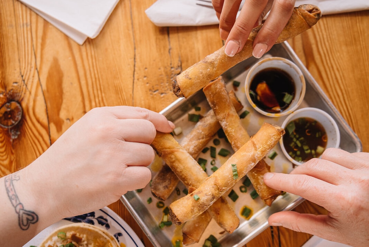 hands holding egg rolls
