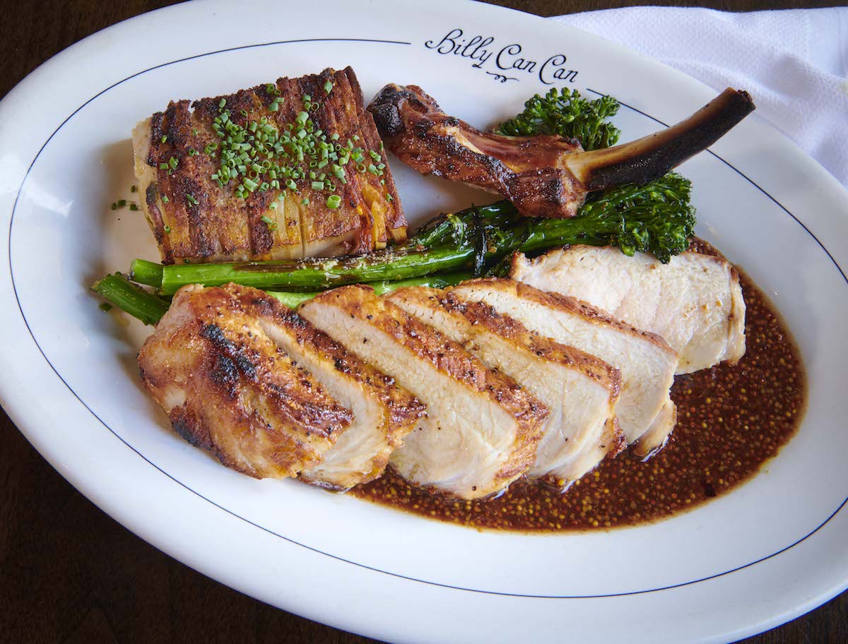 Whiskey-brined, bone-in pork chop with loaded potato pavé, charred broccolini and mustard jus at Billy Can Can. | Photo by Billy Can Can