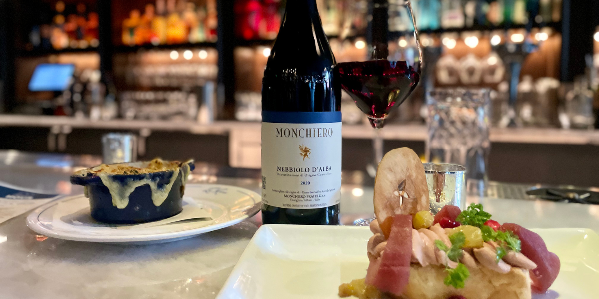 When Fall envelopes the rolling hills of Italy’s Piedmont region, the fog, or ‘nebbia’ that gives the Nebbiolo grape variety its name, floats through the vineyards, cooling the grapes before harvest. This thick-skinned grape produces some of Italy’s finest wines, such as Barolo and Barbaresco. In downtown Denver, this approachable example offers all the flavors and structure we love in this Autumn classic without needing hours of decanting or years of aging in the bottle.

Nestled in the heart of the famed Barolo region in Castiglione Falletto, the Monchiero family has been making remarkable red wines from Nebbiolo since the 1950s. Starting as a grape grower, the family started producing their premium wines in the 70s. The Nebbiolo d’Alba gushes with layered berry flavors and classic notes of violets. Paired with Bistro LeRoux’s classically delicious French Onion Soup and a plate of Foie Gras with Chicken Liver Mousse, the wine offers a pop of tart fruit like a garnish of dried cranberry or cherry. Each of these rich menu items strikes a balance in concert with the wine that screams Fall.
