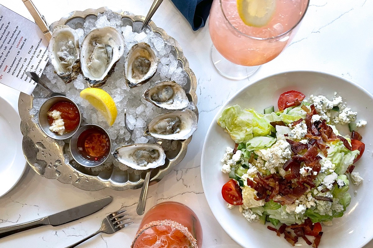 Oysters on ice with sauces and lemon, served with a wedge salad topped with bacon and blue cheese at Blue Island Oyster Bar in Denver.