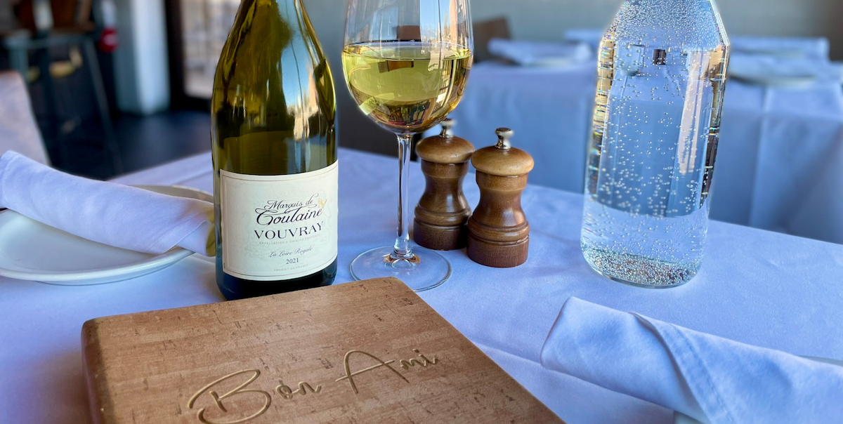wood menu with bottle of white wine, glass of white wine and salt and pepper shakers