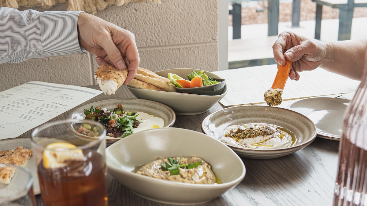 hands reaching for dips and salad