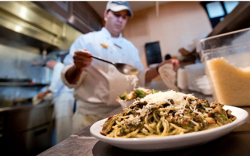 A chef prepares a pasta dish in the kitchen at Buttermilk Mountain Lodge