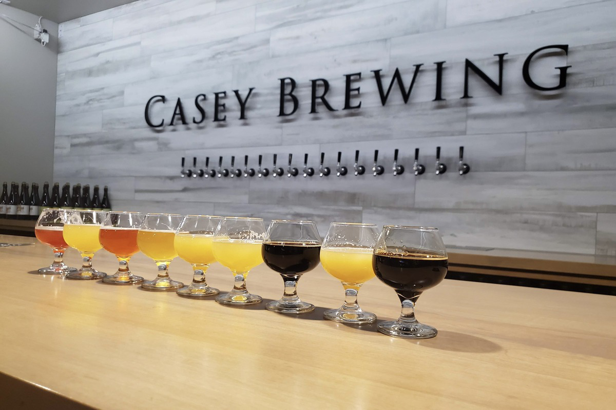 Flight of craft beers at Casey Brewing in Glenwood Springs, Colorado, featuring a colorful range of styles in stemmed glasses lined up on the bar.