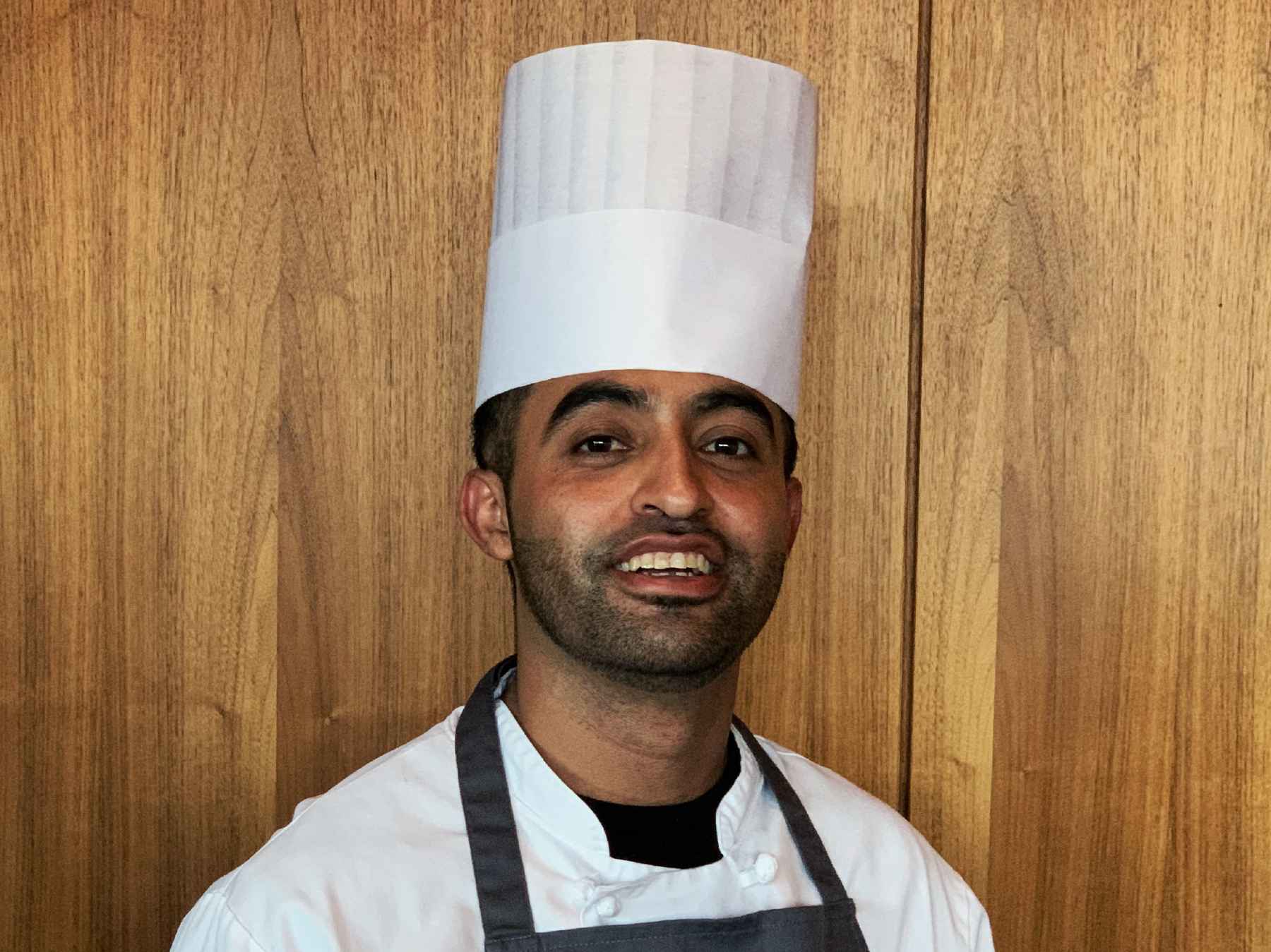 Smiling Mexican man wearing chef's white and toque.