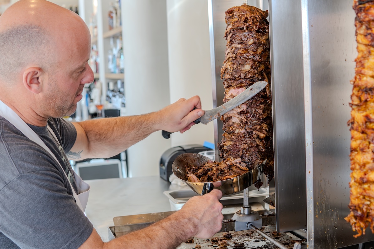 Chase Devitt carves meat at Boychik, his three-restaurant company. | Photo by Boychik