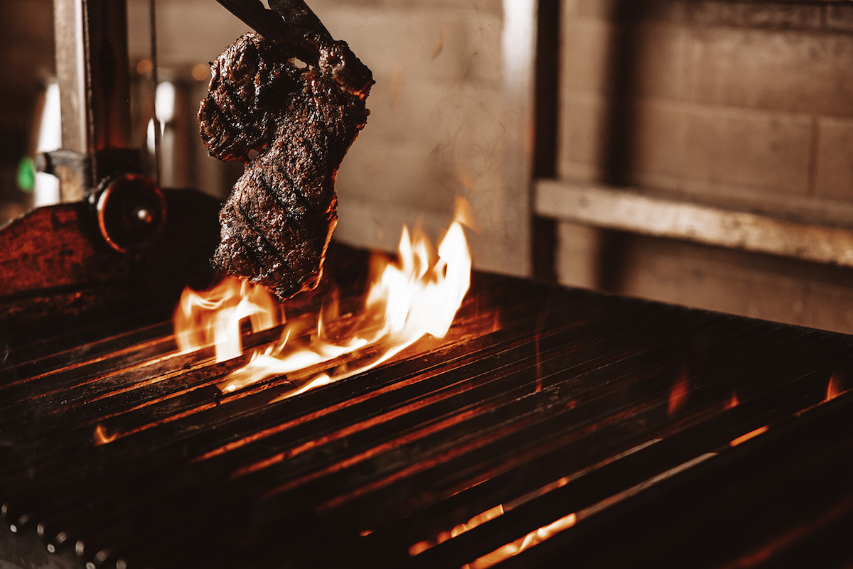 - DiningOut Steak preparation on the wood-fire grill at Flamant. | Photo by Samantha Marie