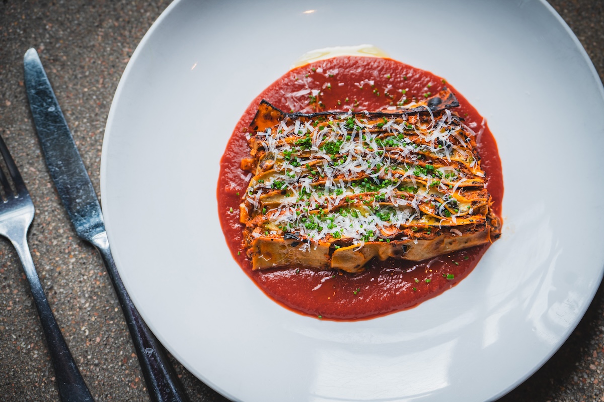white plate with red sauce and lasagna