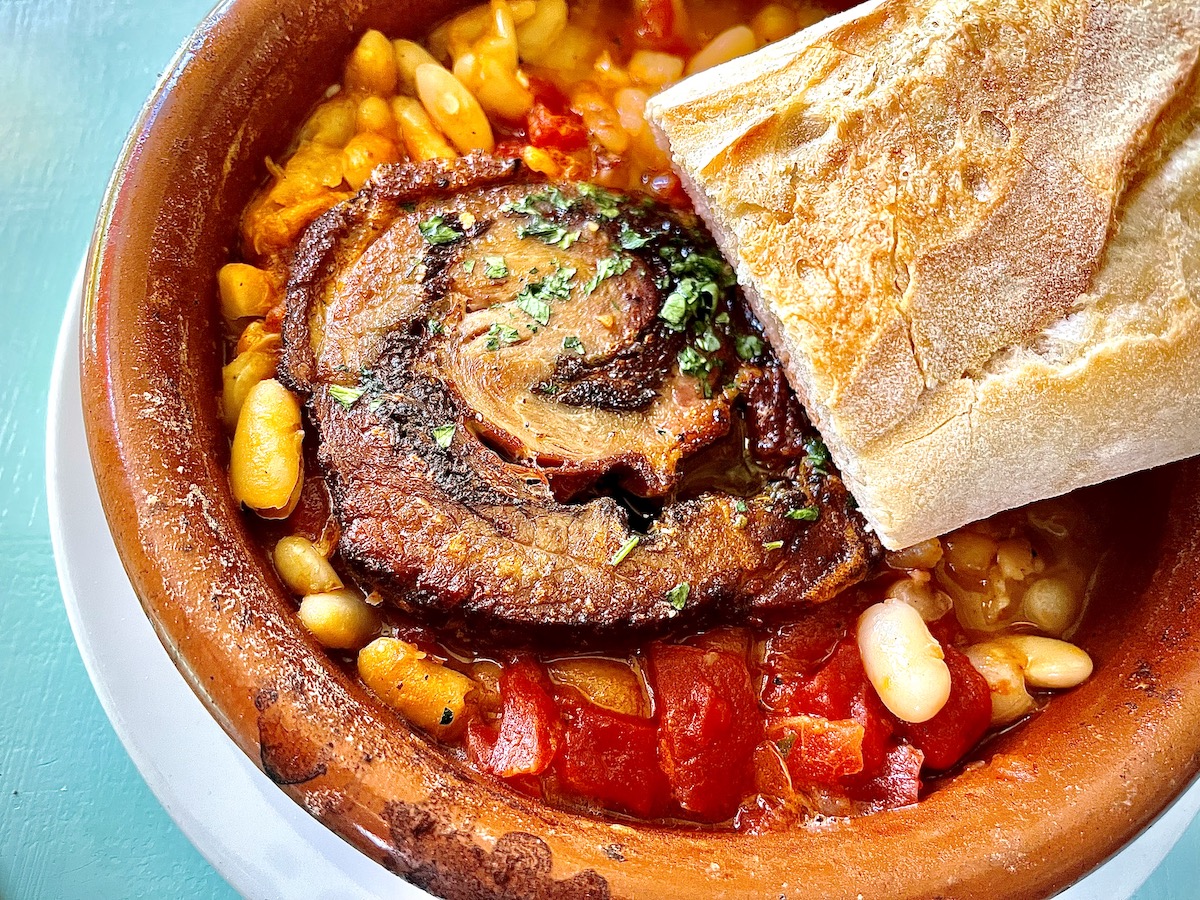 Rosemary-seasoned porchetta (roast pork) with stewed cannellini beans is available in a half order at Giacomo’s cibo e vino. | Photo by Greg Morago