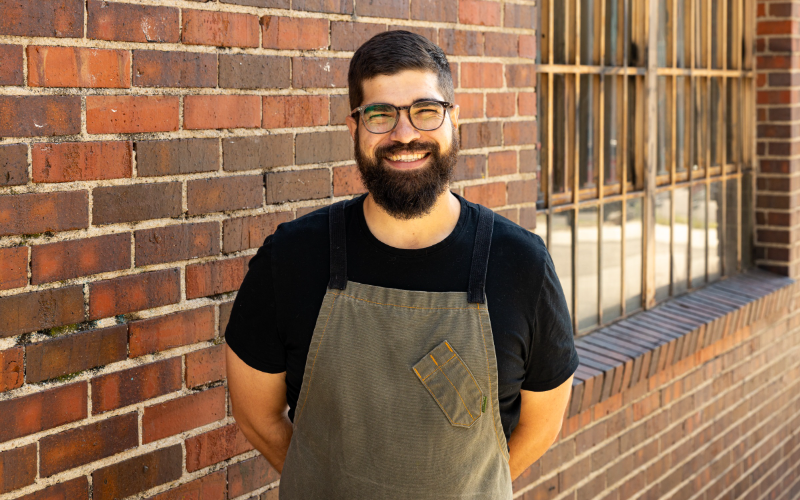 Koko Ni restaurant's Chef de Cuisine James Gnizak stands in front of the restaurant's brick exterior in Denver's RiNo district.