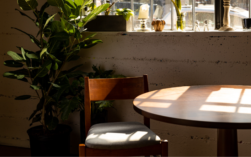 A table and chair in front of a window at Koko Ni restaurant in Denver, Colorado.